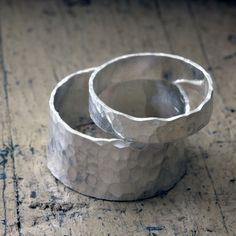 two silver rings sitting on top of a wooden table