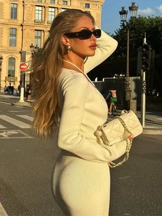 a woman in a white dress is standing on the street