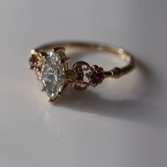 a close up of a ring on a white surface with a light colored diamond in the middle