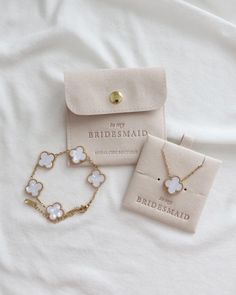 two bridesmaid bracelets and a card case laying on a white bed sheet