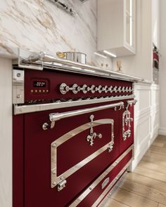 a red stove top oven sitting inside of a kitchen next to a wall mounted oven