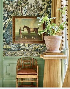 a painting on the wall above a chair with a plant in front of it and a wicker chair next to it