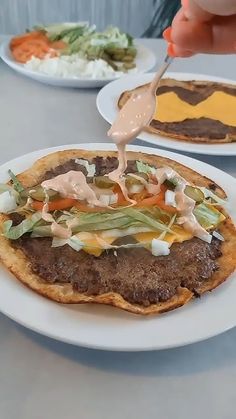 a person is pouring sauce on a plate with food in the background and plates to the side