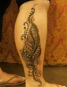 a woman's leg with a tattoo on it that has a peacock feather in the middle