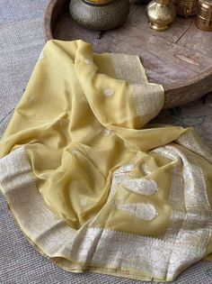 This is a traditional pure banarasi woven georgette saree in beautiful pale yellow colour with an amazing zari weave. Saree features elegantly floriated zari border and pallu. The floral bootis is run throughout the body of the saree. The pallu has paisley bootis in zari weave, the pallu is finished with skill full tassels, which makes it more beautiful. Georgette gives a very beautiful drape owing to its flowy nature. Color: Pale Yellow Length: 5.5 Meters Width: 1.2 Meters Blouse: Running/attac Traditional Gold Georgette Blouse Piece, Elegant Georgette Dupatta With Traditional Patterns, Traditional Georgette Blouse With Zari Weaving, Georgette Dupatta With Zari Weaving, Georgette Saree With Traditional Patterns, Traditional Wear With Zari Weaving In Georgette, Festival Georgette Dupatta With Traditional Patterns, Georgette Traditional Wear For Puja, Semi-stitched Georgette Traditional Wear With Patterns