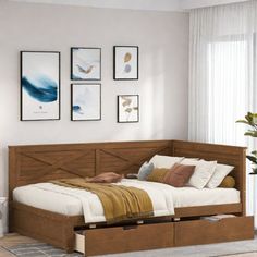 a bed with two drawers underneath it in a living room next to a wall mounted pictures