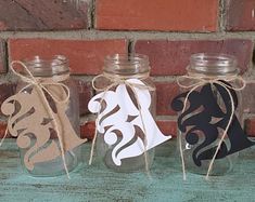 three mason jars with tags tied to them on a table next to a brick wall