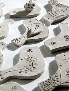 several ceramic ornaments are arranged on a white tablecloth, including one with an ornament in the shape of flowers and leaves