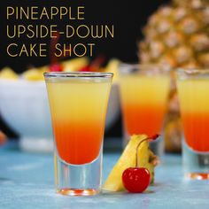 three glasses filled with different colored drinks on top of a blue tablecloth next to pineapples