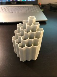 a stack of white cups sitting on top of a table next to a laptop computer