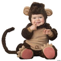 a baby in a monkey costume sitting on the ground with his hands up to his mouth