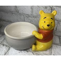 a ceramic winnie the pooh sitting next to a bowl