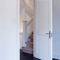 an open door leading to a stairway in a house with white walls and wood floors