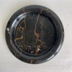 a black and gold marbled plate on a white wall with no one around it