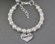 a white bracelet with a heart and flower girl charm