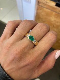 a woman's hand with a green ring on it