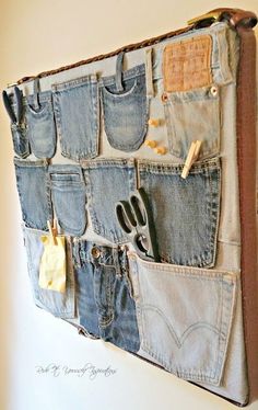 an old pair of jeans hanging on a wall with scissors and other items attached to it