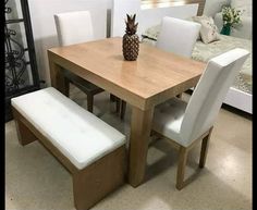 a wooden table with two white chairs and a pineapple vase on top of it