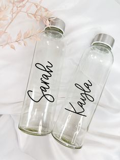 two personalized water bottles sitting on top of a bed