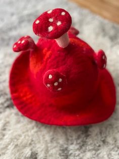 a red toy with white dots on it's eyes and nose is sitting on the carpet