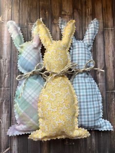 three bunny pillows tied together on a wooden surface with some fabric in the shape of bunnies