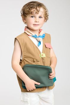 a little boy holding a green purse in his hands