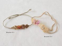 two bracelets with flowers on them sitting on top of a white cloth covered table