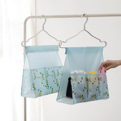 two bags hanging from a clothes line with one bag holding cups and the other carrying bottles