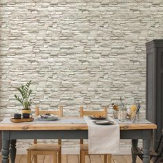 a dining room table with two chairs and a white brick wall behind it