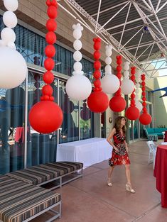 a woman standing under red and white balloons hanging from the ceiling in front of a building