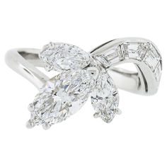 This incredibly chic and uniquely designed vintage diamond ring is crafted in solid platinum and features a breathtaking, GIA certified, marquise brilliant cut diamond neatly prong set on a slightly elevated open basket at the center of the design and is joined with two slightly smaller marquise brilliant cut diamonds on either of its sides. This gorgeous center stone has an absolutely beautiful shape and has been certified by GIA as being a colorless and flawless stone, weighing exactly 1.09 ca Gia Certified Marquise Diamond Ring, Gia Certified Marquise White Gold Diamond Ring, Gia Certified Marquise Diamond Ring Fine Jewelry, Gia Certified Marquise Platinum Rings, Gia Certified Platinum Marquise Rings, Gia Certified Marquise Cut Luxury Diamond Ring, Gia Certified Luxury Marquise Cut Diamond Ring, Luxury Marquise Cut Gia Certified Diamond Ring, Luxury Marquise Diamond Ring With Baguette Diamonds