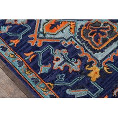 a blue rug with an orange and green design on it, sitting on a wooden floor