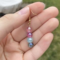 a person holding two small glass beads in their hand, one is blue and the other is pink