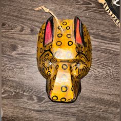 a yellow and black animal mask sitting on top of a wooden table next to a pair of scissors