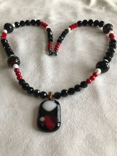 Black,red and white glass fused pendant highlight this beaded necklace which include four multi colored marble shaped beads. Black Glass Jewelry With Large Beads, Black Glass Polished Beads Jewelry, Black Glass Jewelry With Polished Beads, Handmade Black Czech Glass Necklaces, Handmade Black Necklace With Czech Glass, Handmade Black Czech Glass Necklace, Glass Necklace With Black Round Beads, Black Glass Bead Necklace, Black Glass Beaded Necklace With Colorful Beads