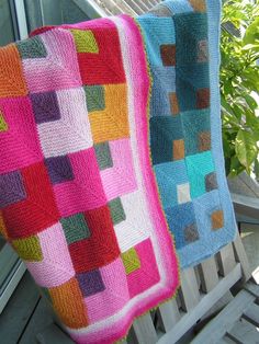 two crocheted blankets sitting on top of a wooden bench