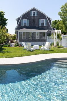 a house with a pool in front of it and lawn chairs next to the pool