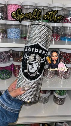 a person holding up a large canister in front of shelves with glitters and other items