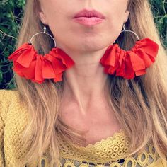 a close up of a person wearing large red flowers on their earring's