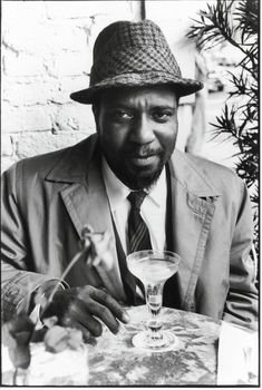 a man wearing a hat sitting at a table with a drink in front of him