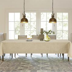 a dining room table with two lamps hanging over it and an area rug on the floor