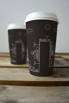 two coffee cups sitting next to each other on top of a wooden table with black and white designs