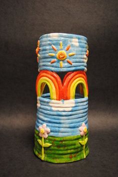 this is a ceramic vase with a rainbow painted on the side and sun above it