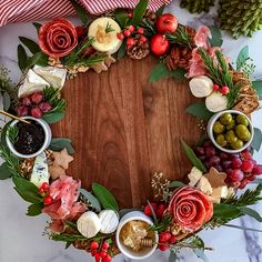 a christmas wreath made out of cheese, meats and vegetables on a wooden board