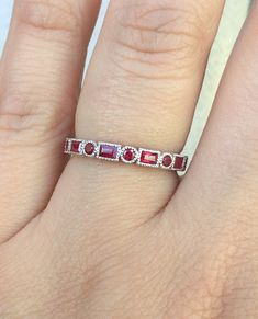 a woman's hand with a red and white diamond ring on top of it