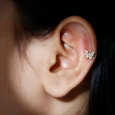 a woman's ear with a small butterfly on top of it, in front of a black background