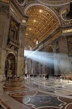 the inside of a building with people walking around and lights coming from it's ceiling