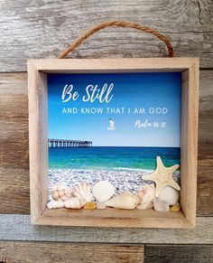 a wooden frame hanging on the wall with seashells and starfish in it