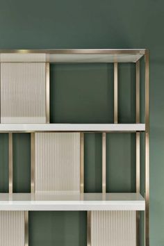 a white book shelf with three shelves on each side and two green walls in the background