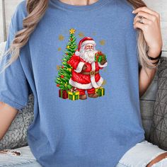 Santa Claus Christmas T-shirt, Cute Santa Claus Shirts, Merry Christmas Shirt, Santa Claus Brought Gifts Shirt, Christmas Gift Shirts Welcome to our store!  We specialize in fashionable products designed to ensure high satisfaction. Please review all the photos provided for detailed views of our items. 💫HOW TO ORDER: To place an order, please select the desired SIZE and COLOR from the drop-down menu for each shirt. You can adjust the quantity for the same color and size as needed. 💫MATERIAL: O Blue Short Sleeve Christmas Top, Christmas Holiday T-shirt With Short Sleeves, Christmas Crew Neck Shirt Gift, Christmas Gift Crew Neck Shirt, Blue Short Sleeve Top For Christmas, Christmas Holiday Short Sleeve T-shirt, Pre-shrunk T-shirt As Winter Gift, Christmas Cotton T-shirt Gift, Christmas Graphic Tee T-shirt As Gift